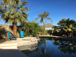 A pool area with palm trees, a blue chair, and a mountain in the background. - Snow Bird Dream For Sunny and warm days during cold northern winters. (Phoenix)
