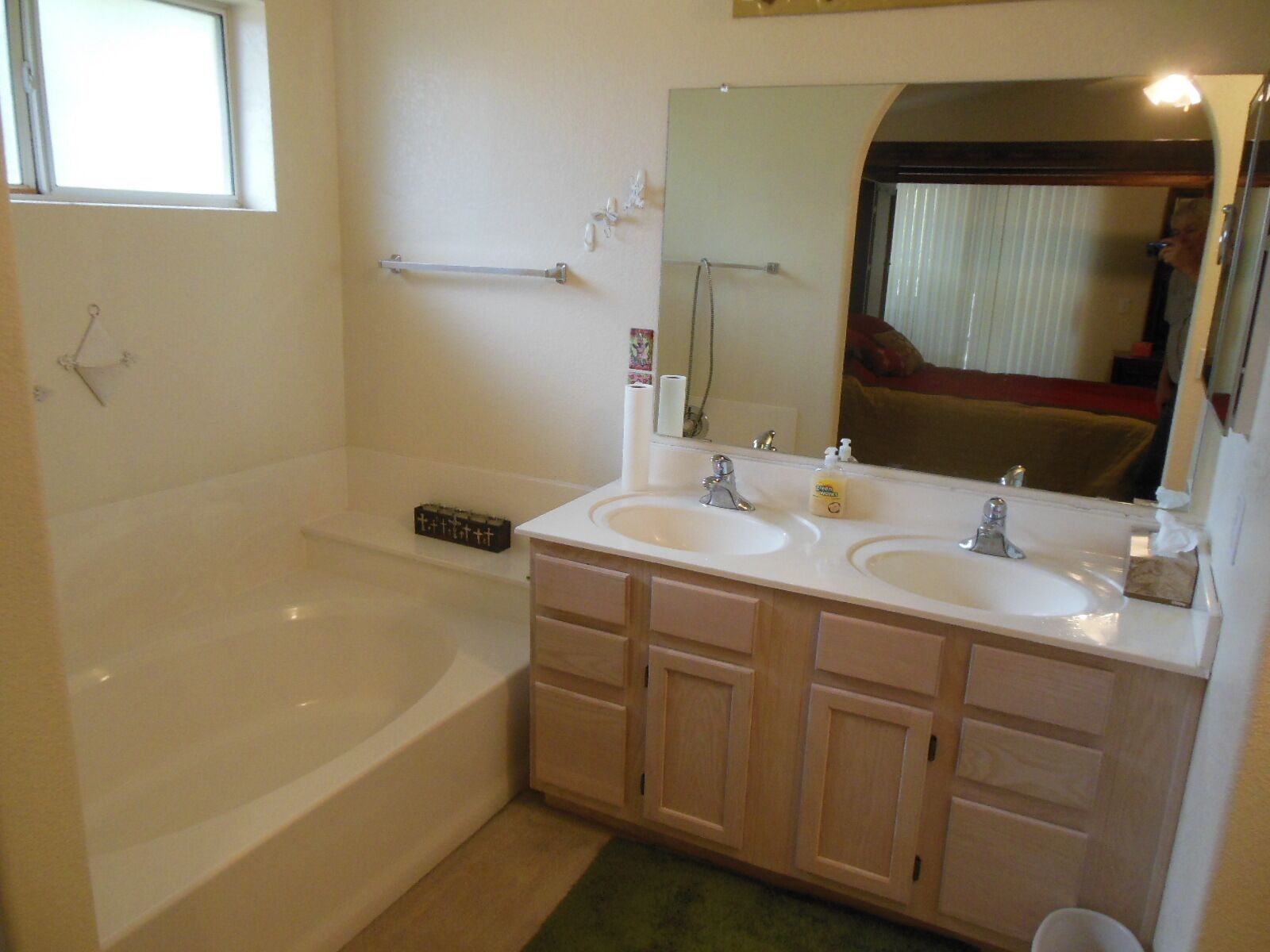 A bathroom with a bathtub, two sinks, a large mirror, and a towel rack.