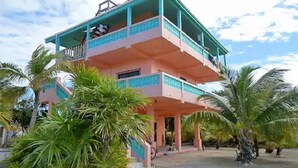 A multi-story building with balconies, surrounded by palm trees. - Oceanfront home; Rooftop deck; Fabulous views; Upper level apartment (Caye Caulker)