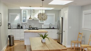 Une cuisine moderne avec des meubles blancs, une table à manger en bois et un réfrigérateur en acier inoxydable.