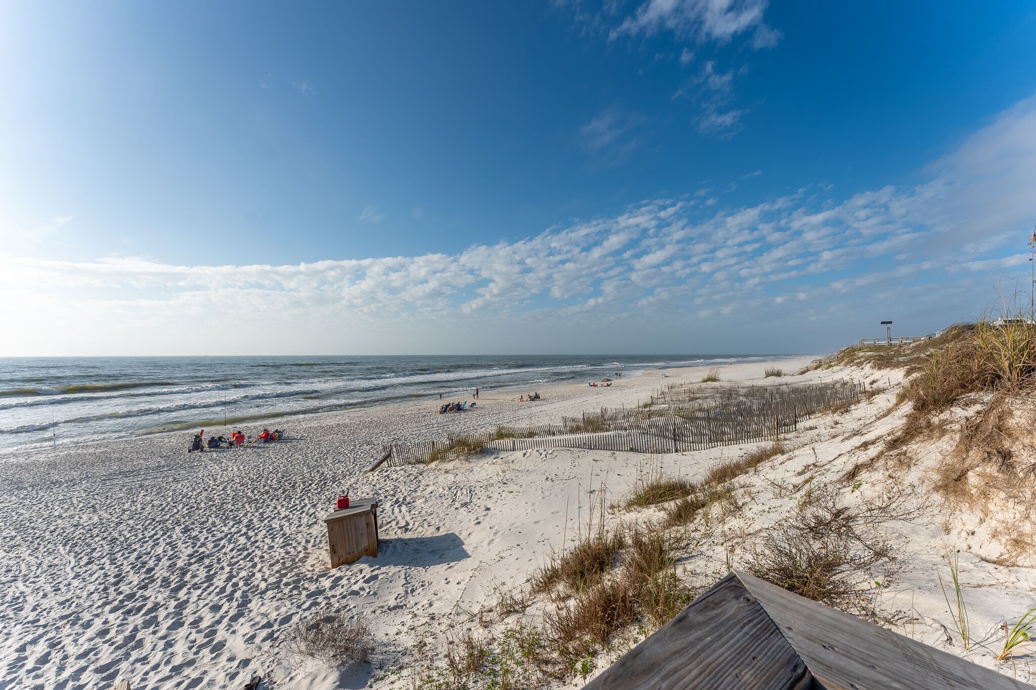 Een strand met een houten vogel kijken, zandduinen en een heldere lucht.