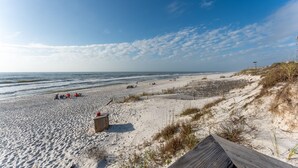 Une plage avec une promenade en bois, des dunes de sable et un ciel dégagé.