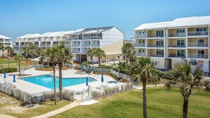 Un hôtel à plusieurs étages, doté d’une piscine et bordé de palmiers.