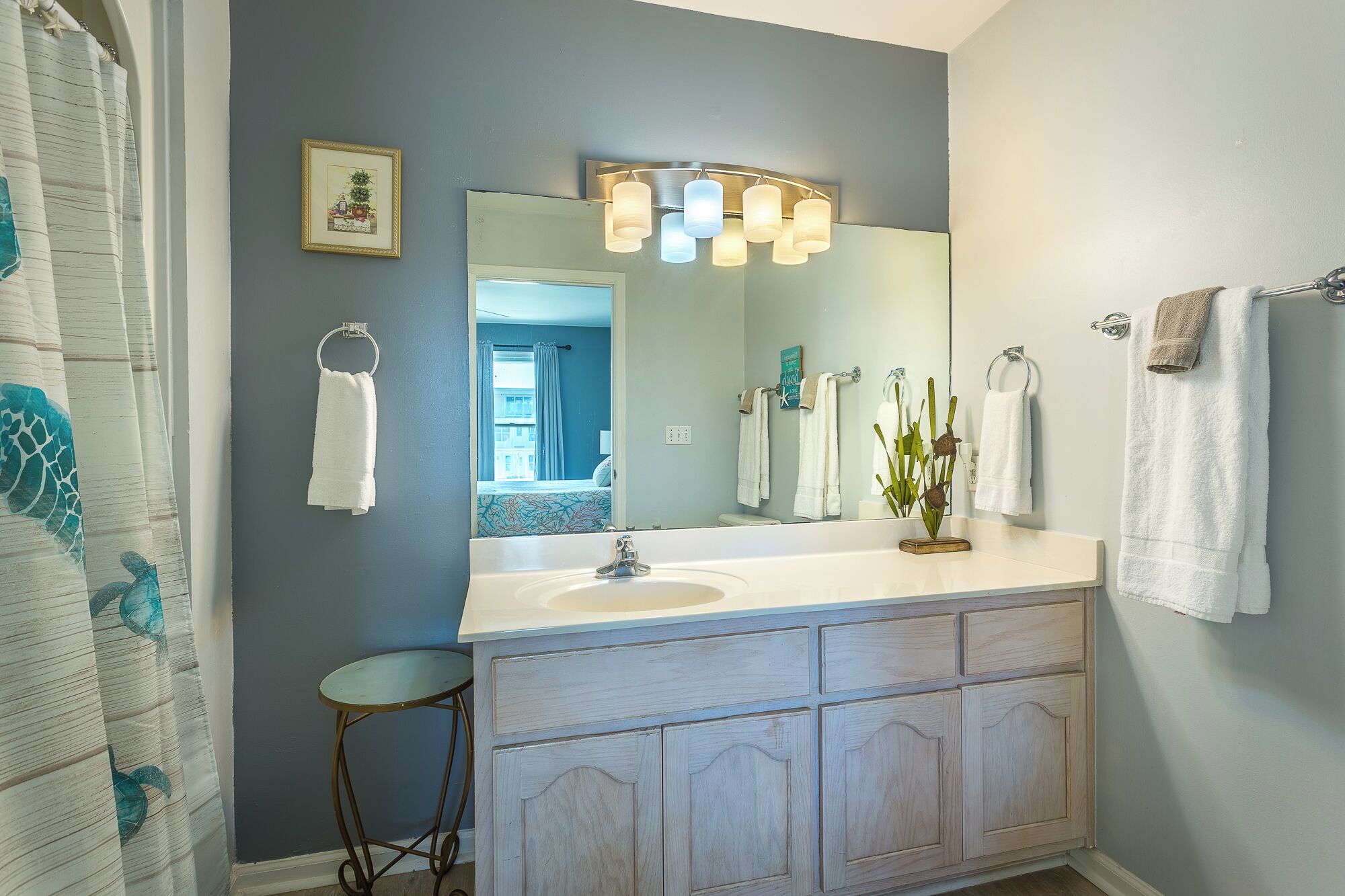 A bathroom with a large mirror, white vanity, and multiple towels.