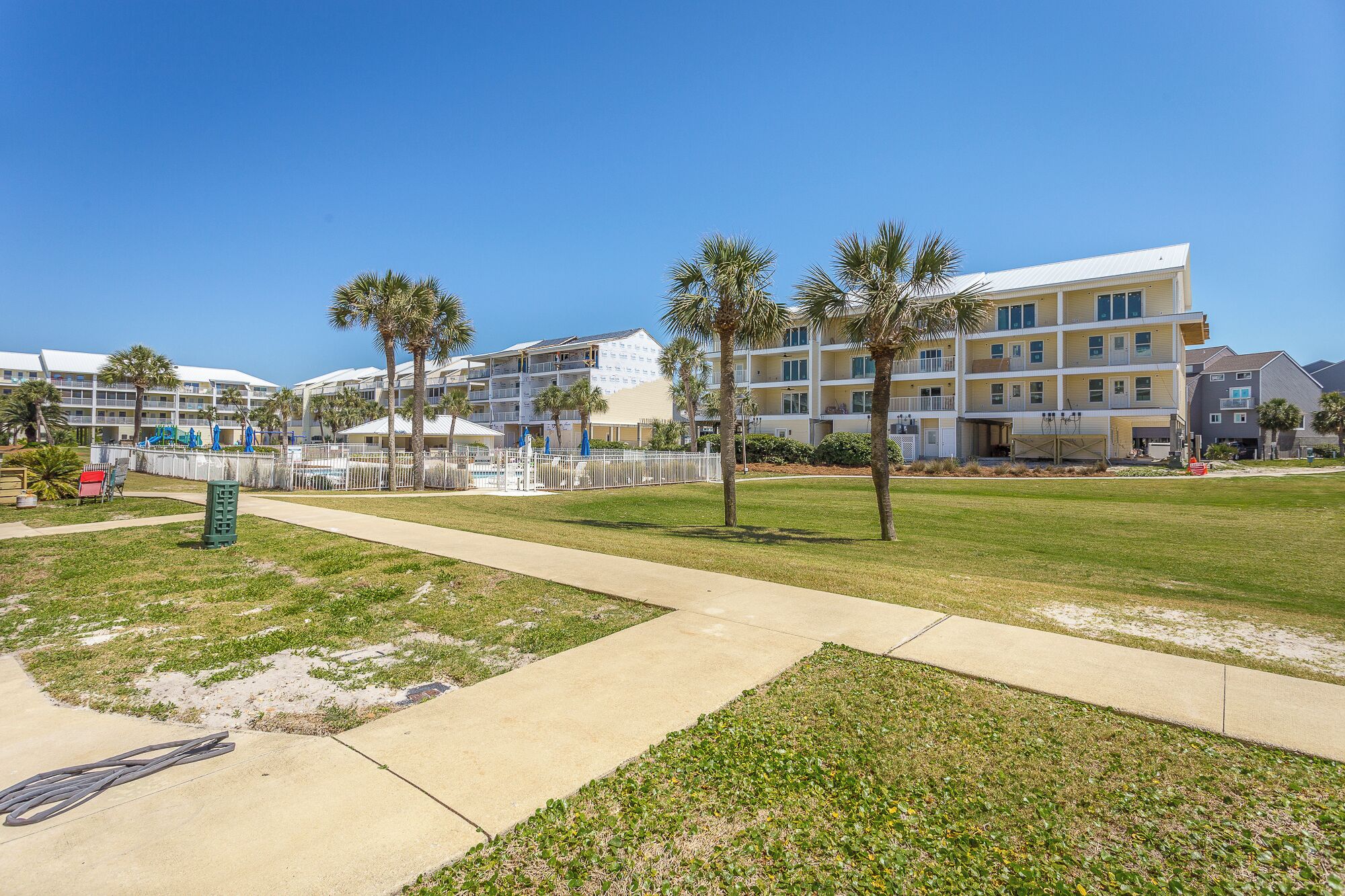 A resort with multiple-story buildings, a pool area, and palm trees.