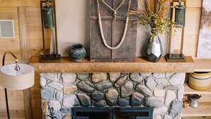 Un saló d'estar acollidor amb una llar de pedra, mobles de cuir i decoració rústica.