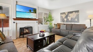 A living room with a fireplace, a television, a sofa, and a coffee table. - Relaxing Lakefront-Pool-Spa-Pontoon-Game Room-FirePits-Cardinal Stadium-WM Open (Glendale)