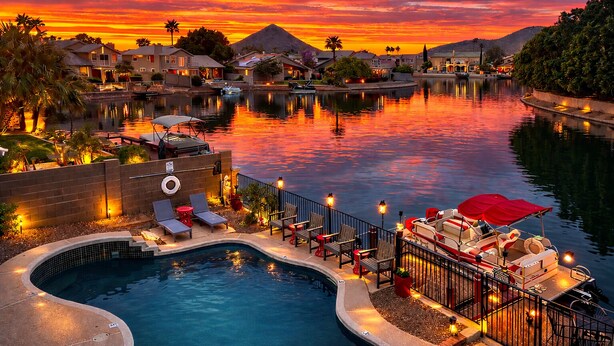 A swimming pool with lounge chairs and a boat docked by the water. - Relaxing Lakefront-Pool-Spa-Pontoon-Game Room-FirePits-Cardinal Stadium-WM Open (Glendale)