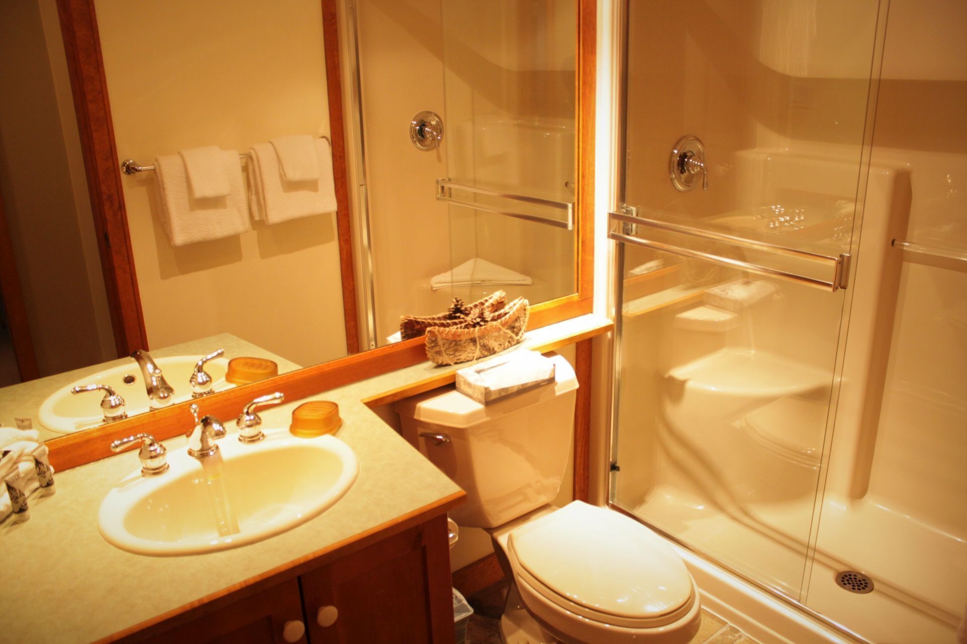A bathroom with a sink, mirror, toilet, and glass-enclosed shower.