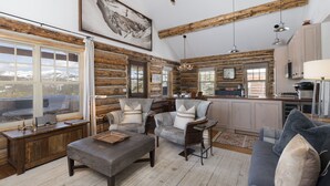 Ein Holzblockhaus-Interieur mit einer gemütlichen Sitzecke, Holzwänden und einer Küche mit modernen Geräten.