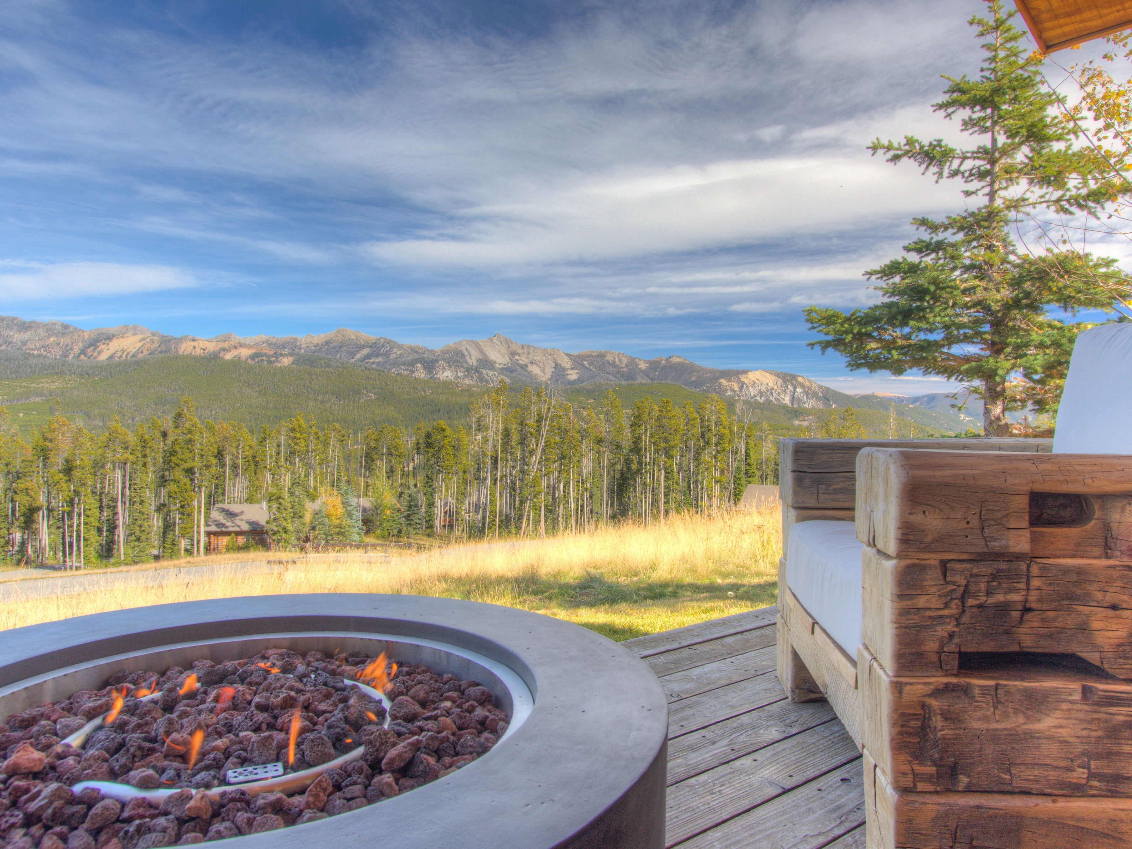 A fire pit with a view of mountains and trees.