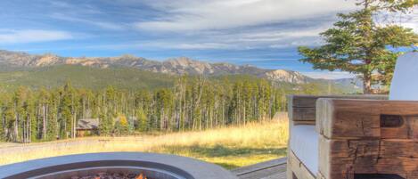 A fire pit with a view of mountains and trees.