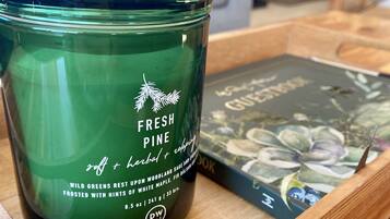 Ein grünes Kerzenlicht mit dem Aufdruck "FRESH PINE" auf einer Holzschale.