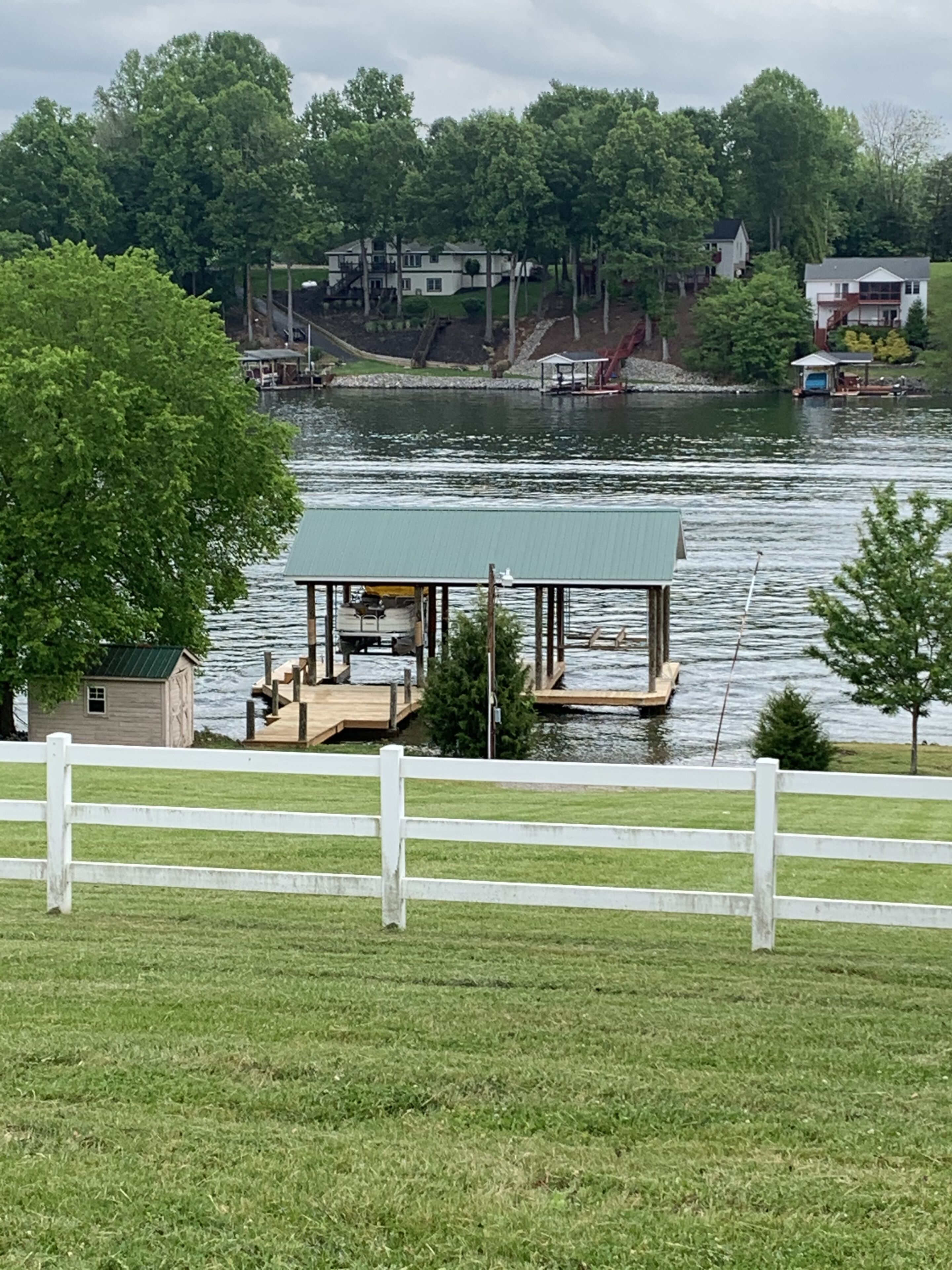 A lakeside dock with a covered seating area and a small shed.