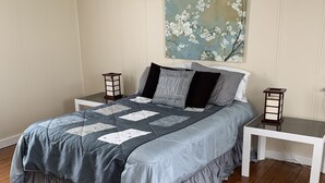 A bedroom with a bed, a nightstand, a wall-mounted painting, and a ceiling fan. - The Olde Farmhouse Spacious Lakefront House with Amazing View (Goodview)