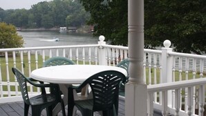 A deck with a white railing, a round table, and two chairs. - The Olde Farmhouse Spacious Lakefront House with Amazing View (Goodview)