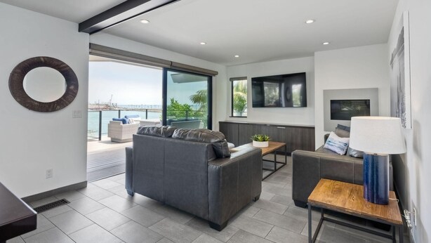 A modern living room with a grey sofa, a wooden coffee table, and a TV mounted on the wall. - Kai Entire Home (5 bedroom / 5 bath) (Carlsbad)
