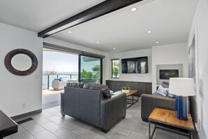 A modern living room with a grey sofa, a wooden coffee table, and a TV mounted on the wall.