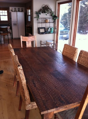 Enjoy meals in this dining area with a large table and comfortable chairs, offering a view of the outdoors.