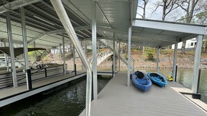 A covered dock with kayaks and a boat ramp leading to a body of water. - Dancing Bream, Lakefront, Dock, Sun Deck, kayaks, Hot tub. (Hiawassee)