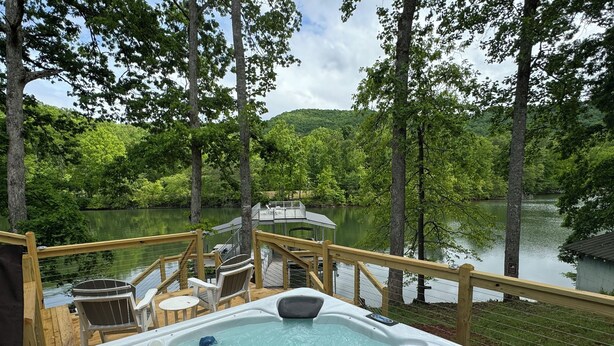 A hot tub on a wooden deck with a view of a lake and forest. - Dancing Bream, Lakefront, Dock, Sun Deck, kayaks, Hot tub. (Hiawassee)