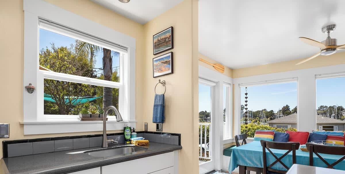 Una cocina con un lavamanos, una ventana y una zona comedor con mesa y sillas.