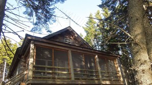 A wooden cabin with a balcony, surrounded by trees. - Come, relax, and enjoy true peace and beauty. (Milbridge)
