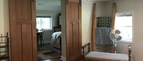 Una habitación con cama, banca, ventilador y puerta corredera.