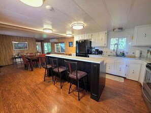 A spacious kitchen with a central island, bar stools, and a dining area with a wooden table and chairs.