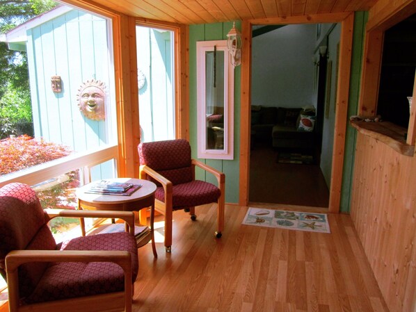 A cozy wooden room with a wooden ceiling, a small round table, and two patterned chairs.