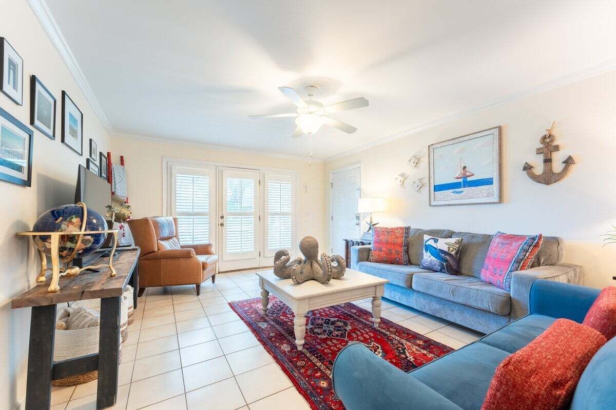 A living room with a blue sofa, a brown armchair, a coffee table, and a red rug.
