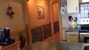 Una cocina con un arco de madera que da a un comedor, una cafetera en la encimera y una isla de cocina con un fregadero.