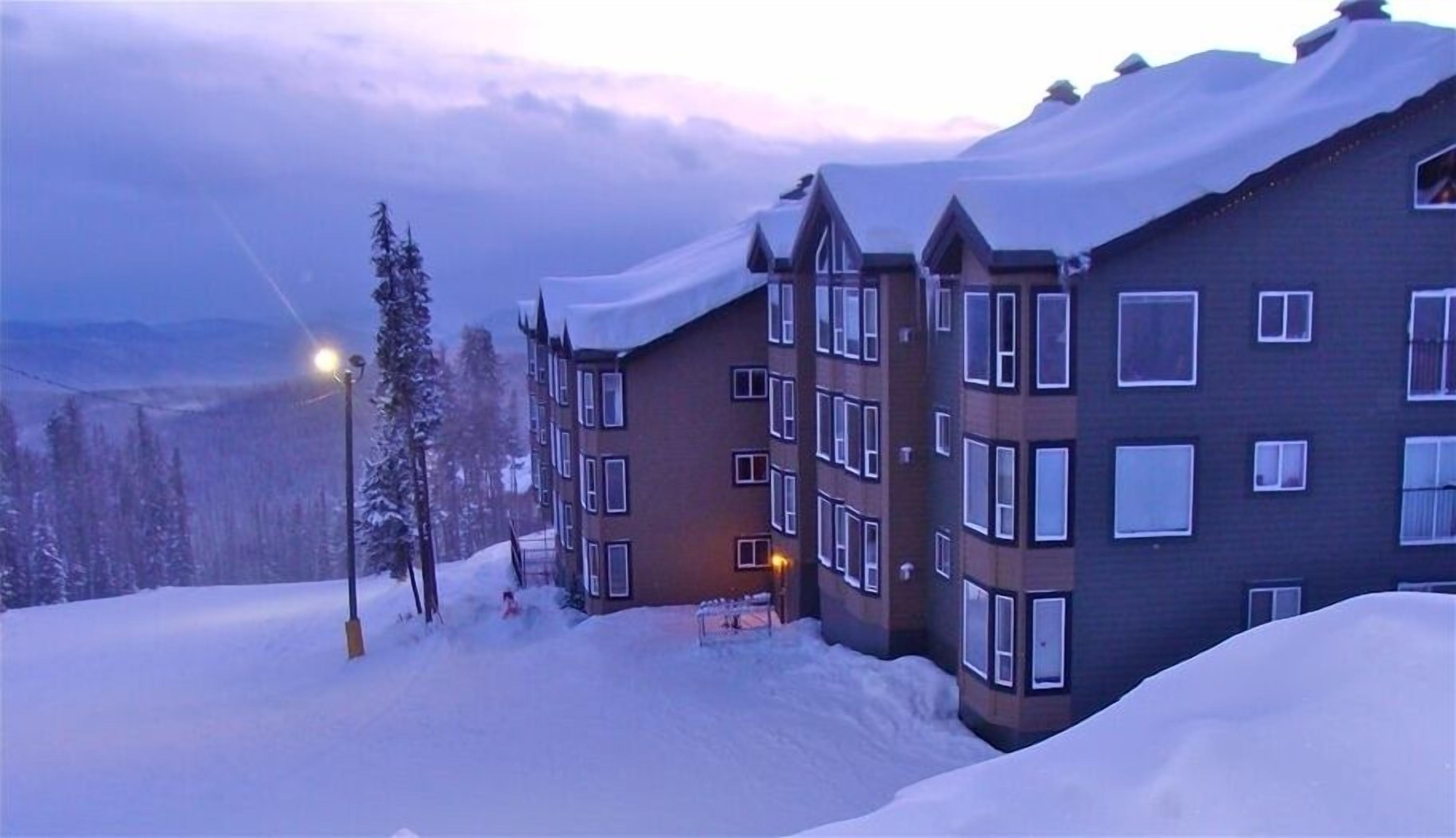 A multi-story hotel with a snow-covered exterior, a visible staircase, and a street lamp.