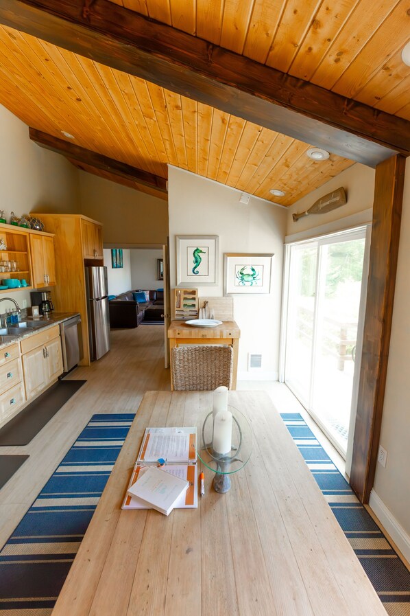 A modern kitchen with wooden cabinets, a stainless steel refrigerator, and a dining area with a table and chairs.