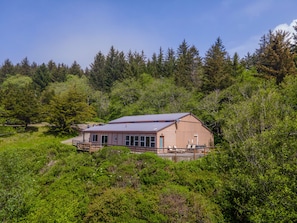 Un bâtiment d’un seul étage, doté d’un toit en pente, entouré d’une forêt dense.