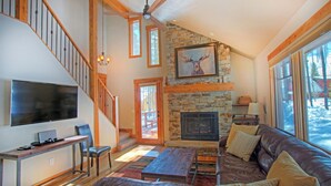 A spacious living room with a stone fireplace, leather sofa, and a television. -  The Perfect Family Mountain Getaway (Breckenridge)