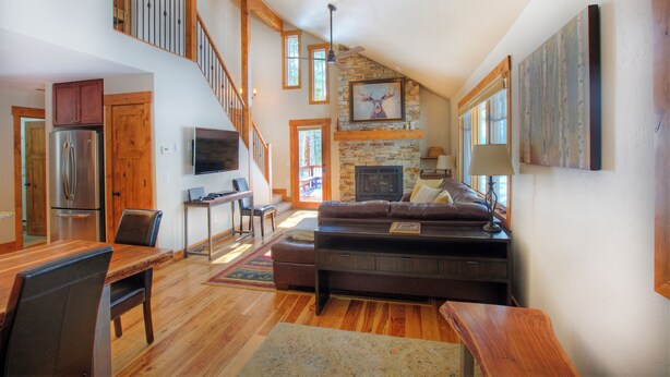 A spacious living area with a fireplace, wooden furniture, and a staircase leading to an upper level. -  The Perfect Family Mountain Getaway (Breckenridge)