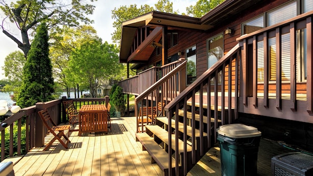 A wooden deck with outdoor furniture, a staircase, and a view of a lake. - Beautiful 7 Bed, 6 Bath, Huge Dock, Boat Launch @ House, Game Room, Kid Friendly (Sunrise Beach)