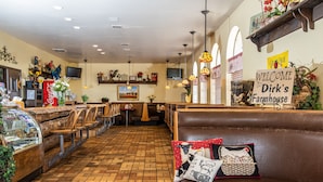 A restaurant interior with wooden flooring, leather seating, and a 'Welcome to Dirk's Farmhouse' sign. - Manti Country Village Motel (Manti)