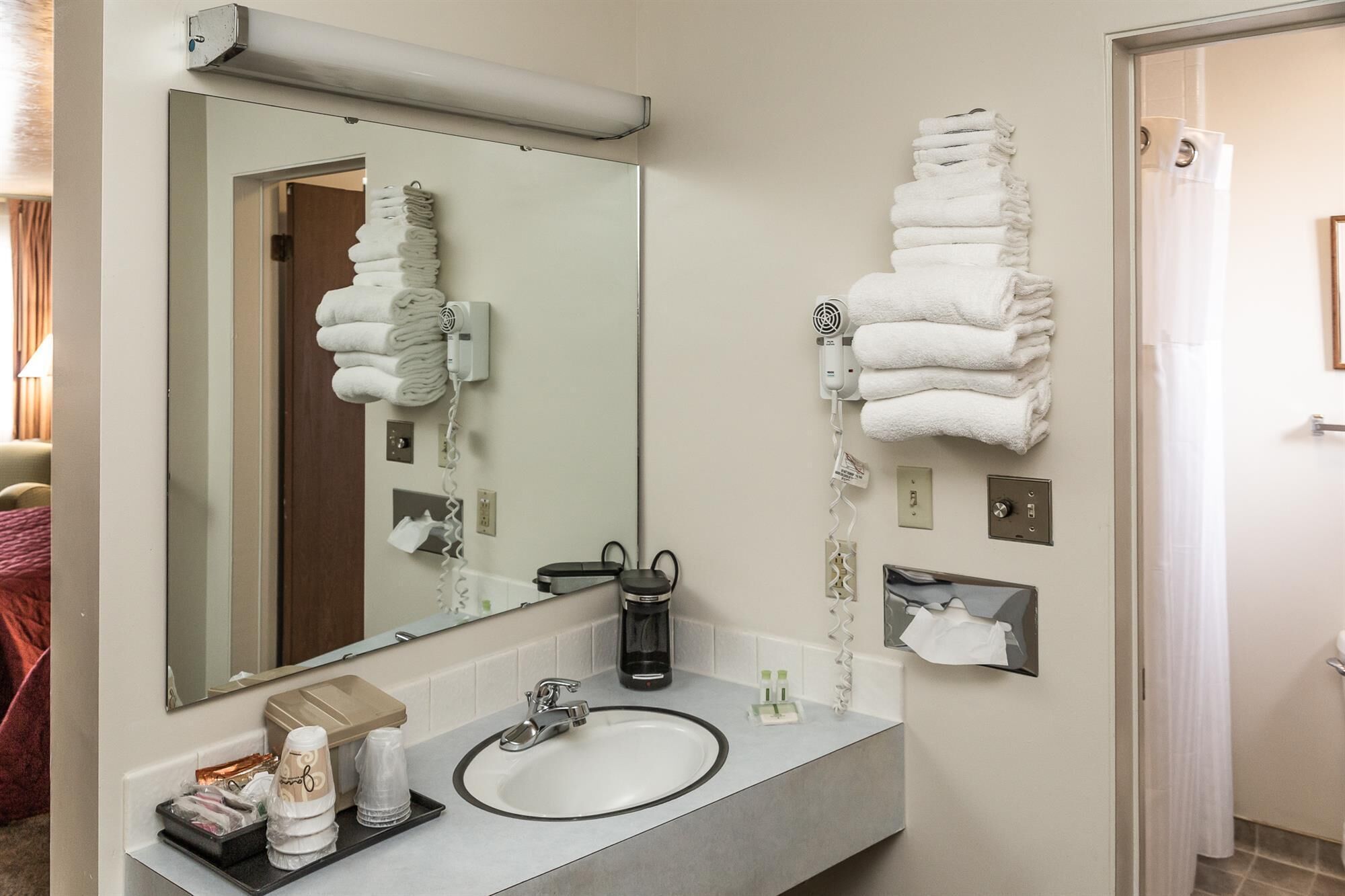 A hotel bathroom with a large mirror, a sink, and two towel warmers mounted on the wall.