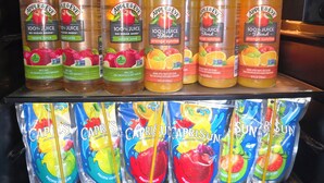 A refrigerated display of beverages including Apple & Eve apple juice, orange sunrise blend, and Capri Sun fruit punch. - Manti Country Village Motel (Manti)