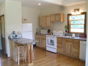 Enjoy cooking in this well-equipped kitchen with a central island and stools, featuring a refrigerator, microwave, stove, and sink.