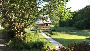A house with a porch, surrounded by a grassy yard and trees. - Garden Cottage near Asheville and Blue Ridge Parkway (Fairview)