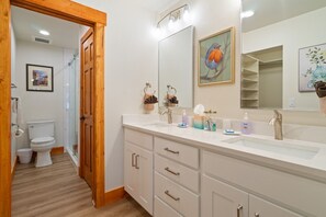 Une salle de bain avec un double lavabo, une porte en bois et un grand miroir.