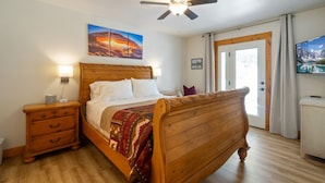A bedroom with a wooden bed, a nightstand, a ceiling fan, and a painting on the wall. - Minutes to mountains resorts & downtown SLC (cottonwood heights)