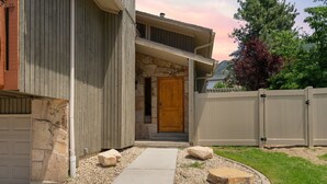 A two-story building with a stone facade, a wooden door, and a concrete pathway leading to the entrance. - Minutes to mountains resorts & downtown SLC (cottonwood heights)
