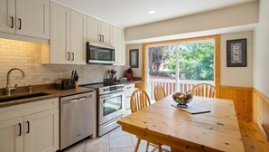 A kitchen with white cabinets, a microwave, a sink, and a wooden dining table with chairs. - Minutes to mountains resorts & downtown SLC (cottonwood heights)