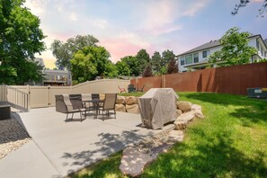 Un jardin avec une terrasse, du mobilier d’extérieur et un espace barbecue couvert.