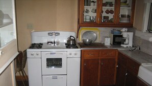 A compact kitchen with a stove, oven, and wooden cabinets. - Bemus Point Vacation Rental (Bemus Point)