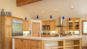 Un'ampia cucina con mobili in legno, un frigorifero in acciaio inossidabile, un forno a microonde e una grande isola con lavello.